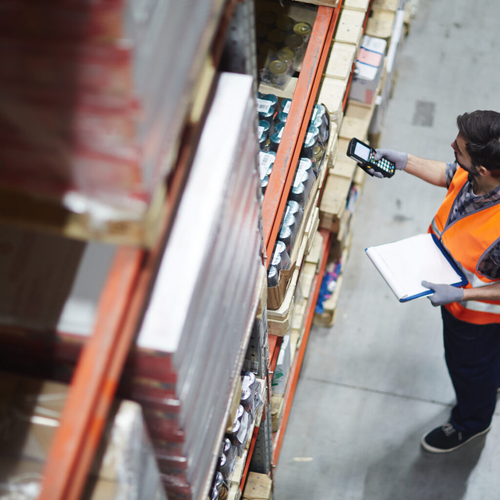 Worker with scanner making review of goods in warehouse